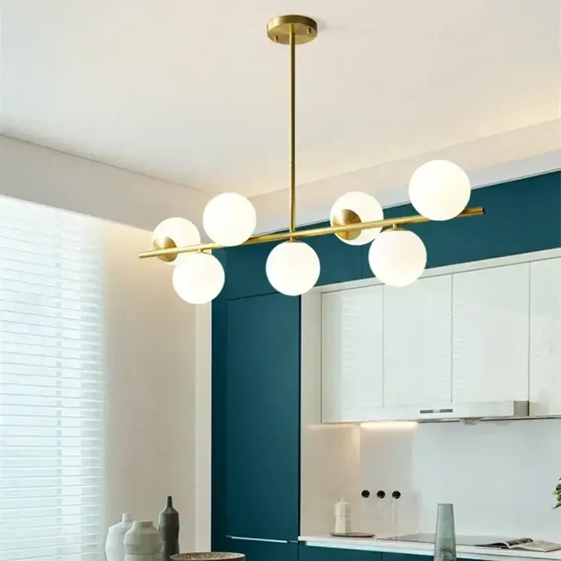 Modern gold bean glass chandelier features a brass pendant light with six frosted glass globe bulbs in a linear design