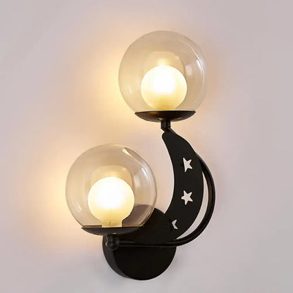 Modern gold and black ball wall sconce with crescent moon shape, cut-out stars, and two clear glass globe shades