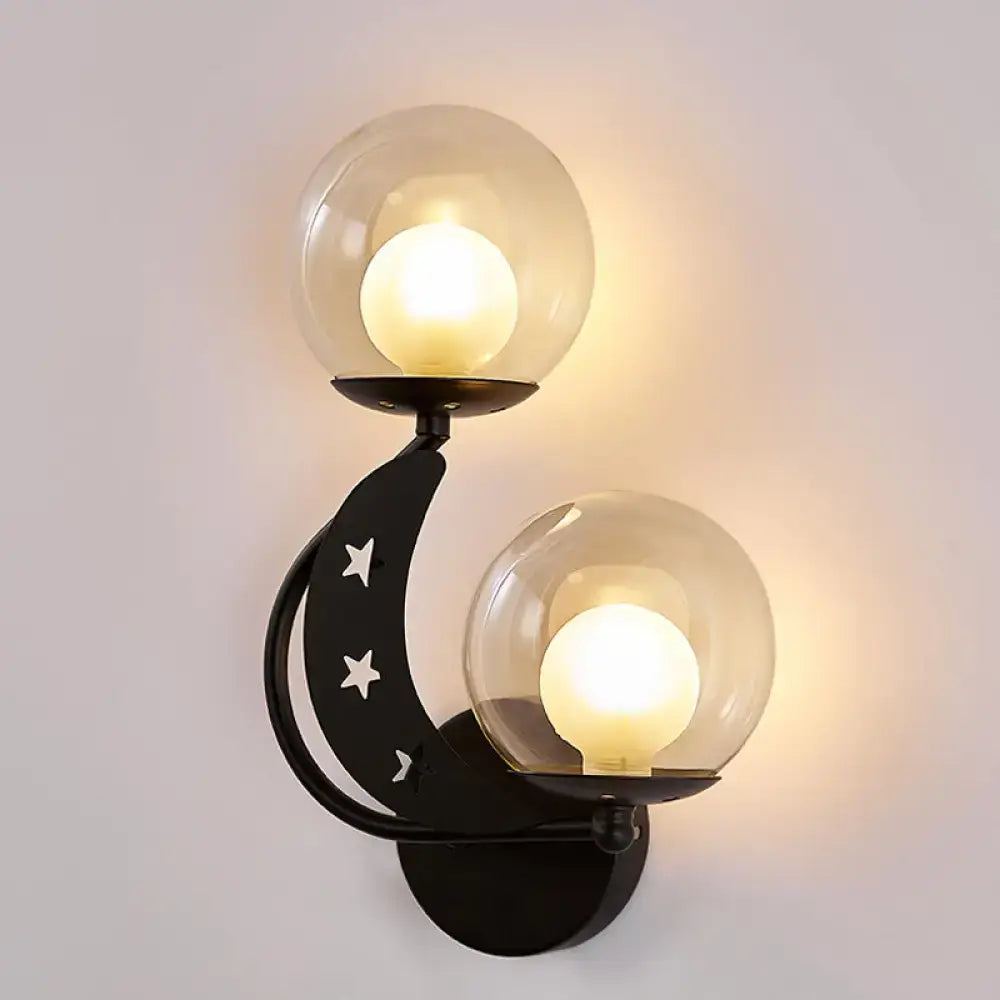 Modern gold and black ball wall sconce featuring a black crescent moon shape with two clear glass globes and white star cutouts