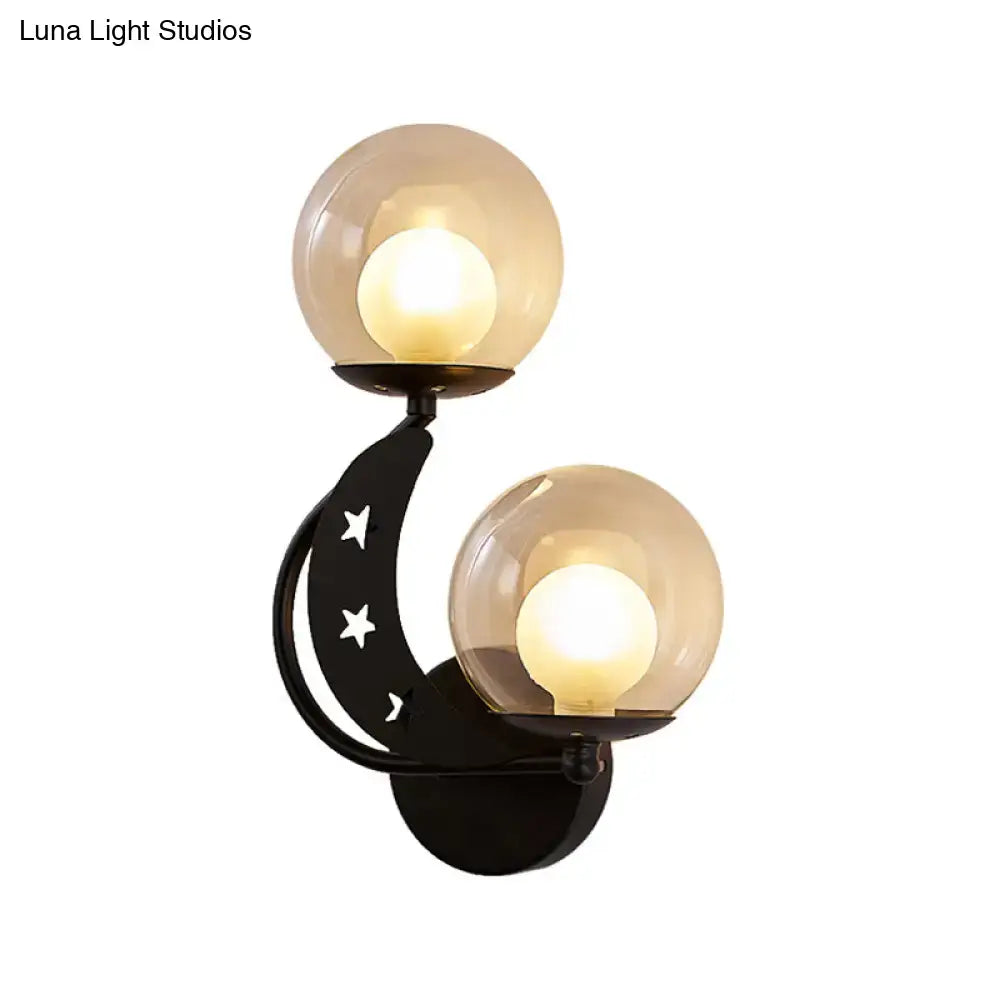 Modern gold and black ball wall sconce featuring black crescent moon shape with star cutouts and two amber glass globes
