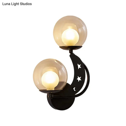 Modern gold and black ball wall sconce with black crescent moon shape, star cut-outs, and two frosted glass globe shades