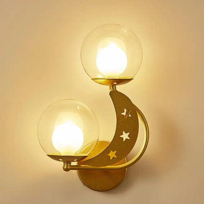 Modern gold and black ball wall sconce featuring a crescent moon shape with cut-out stars and two glass globe lights