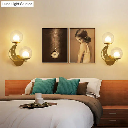 Modern gold and black ball wall sconce with dual spherical glass shades and crescent moon designs for bedroom lighting