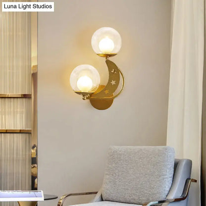 Modern gold and black ball wall sconce featuring a gold-toned crescent moon with frosted glass globes and star cutouts