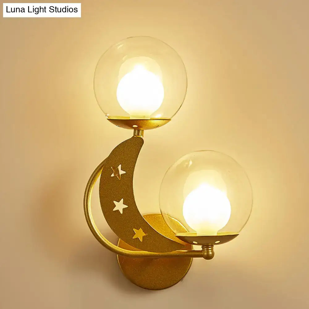 Modern gold-toned crescent moon ball wall sconce with two clear glass globe shades and star cutouts for bedroom lighting
