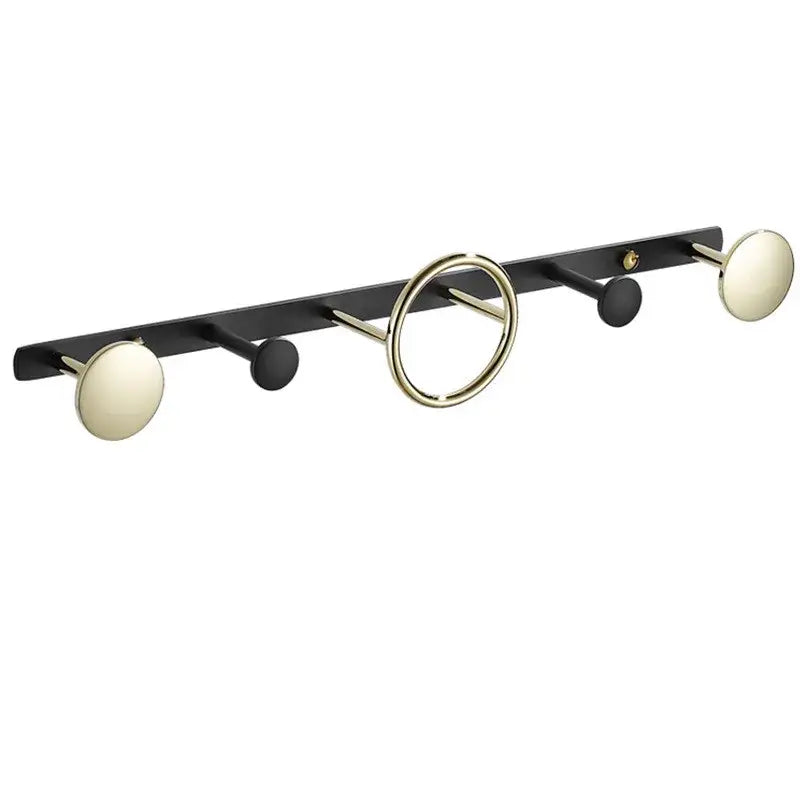 Modern gold and black brass towel hook set featuring round knobs, cylindrical hooks, and a circular ring for wall mounting