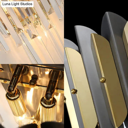 Modern gold and black sconce light fixture with cascading crystal prisms and metallic accents for bedroom walls