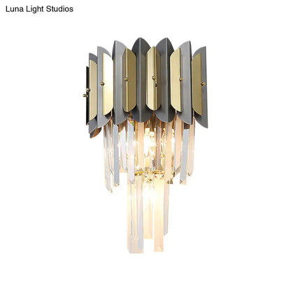 Modern gold and black sconce light fixture with metallic leaf plates and cascading crystal prisms for bedroom walls