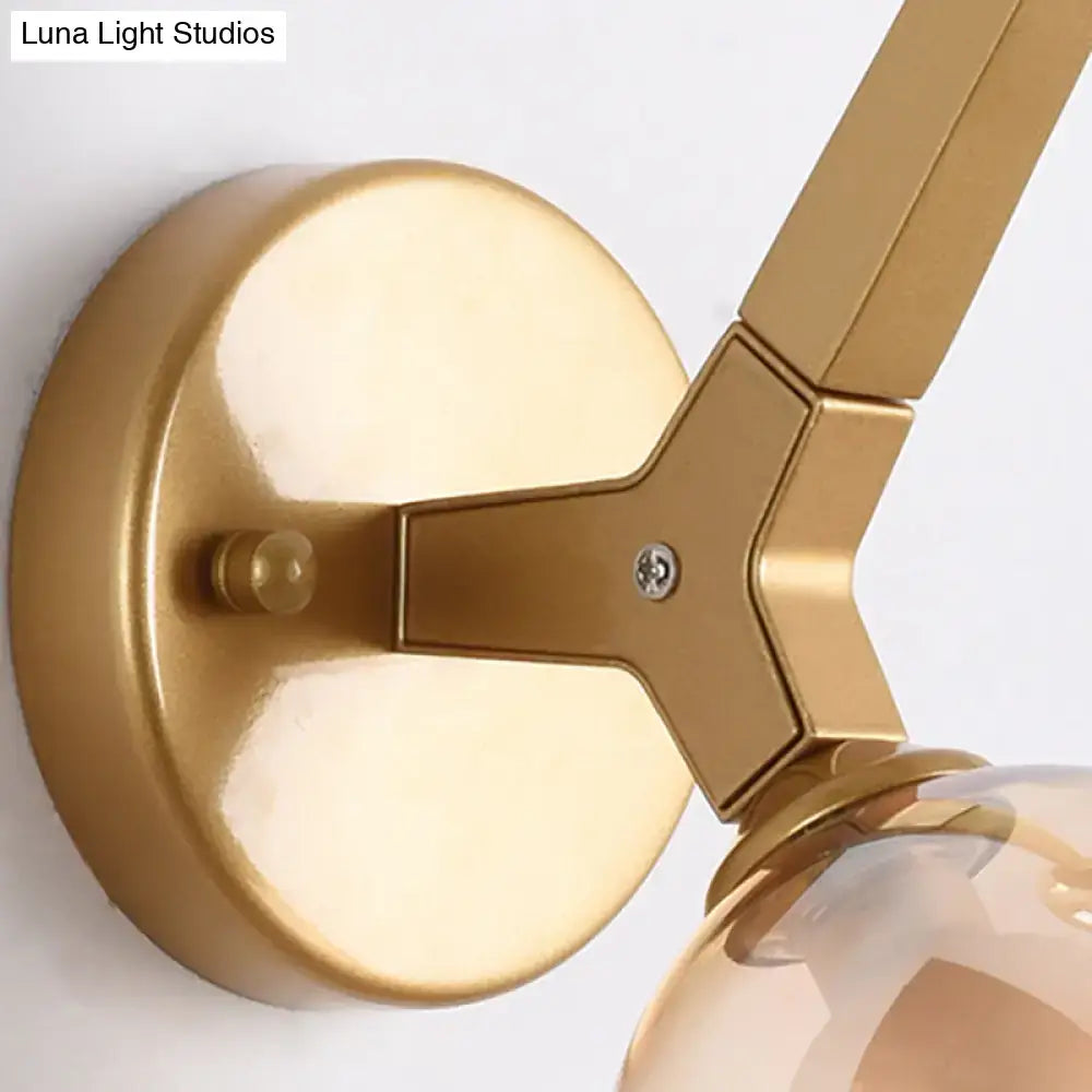Modern gold and black double globe wall lamp with gold-finished metal y-shaped arm and clear glass bulb globe wall lamp