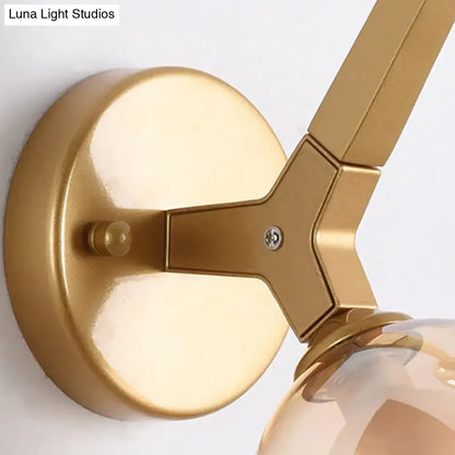 Modern gold and black double globe wall lamp with gold-finished metal y-shaped arm and clear glass bulb globe wall lamp