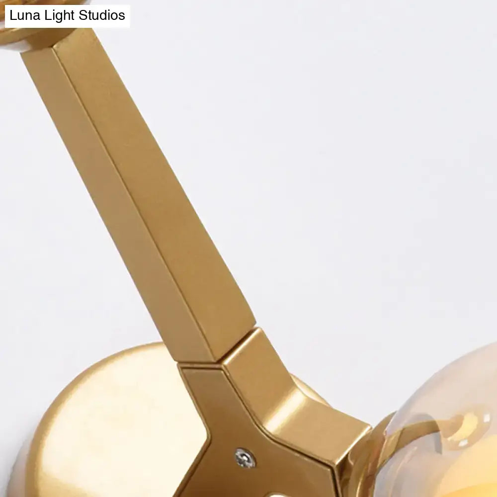 Modern gold and black double globe wall lamp featuring a gold-finished metal arm with a sleek angular design