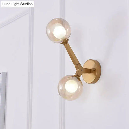 Modern gold and black double globe wall lamp featuring a gold-toned wall sconce with two amber glass globes