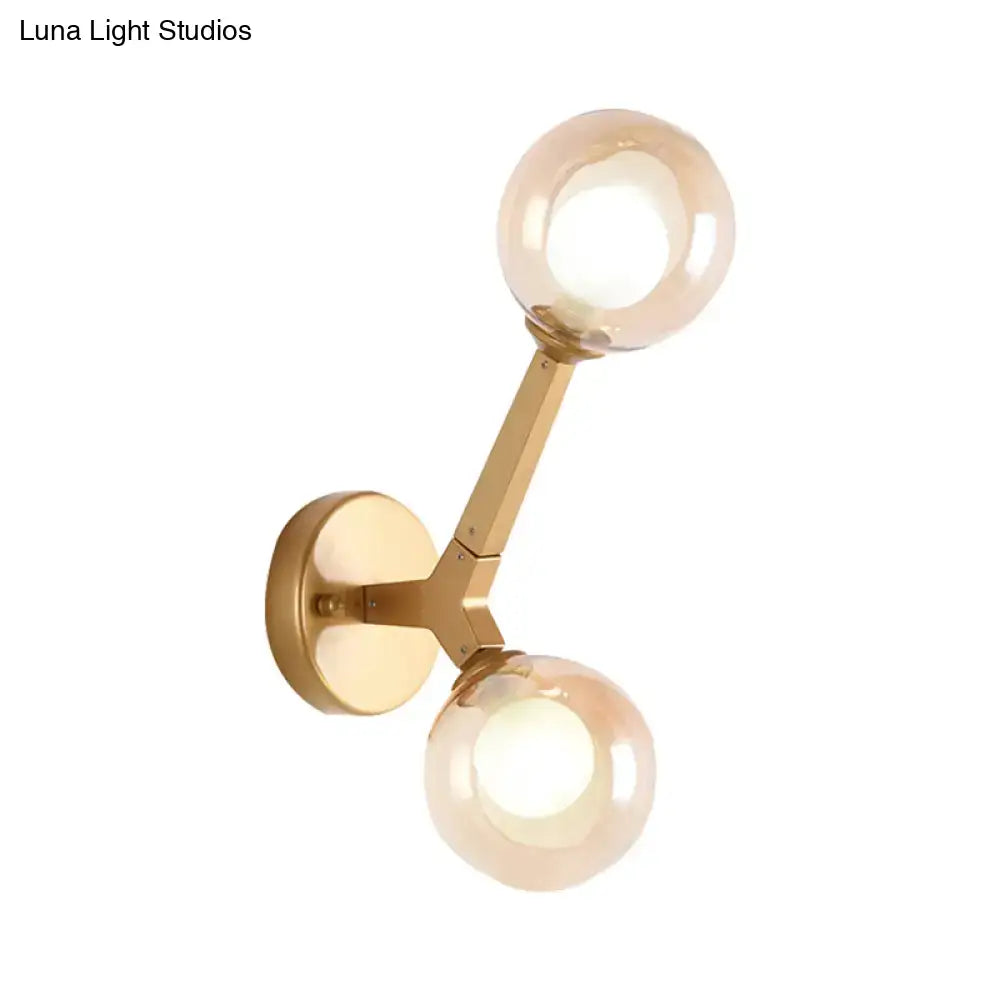Modern gold and black double globe wall lamp features a gold-toned sconce with amber-tinted glass globes for corridors