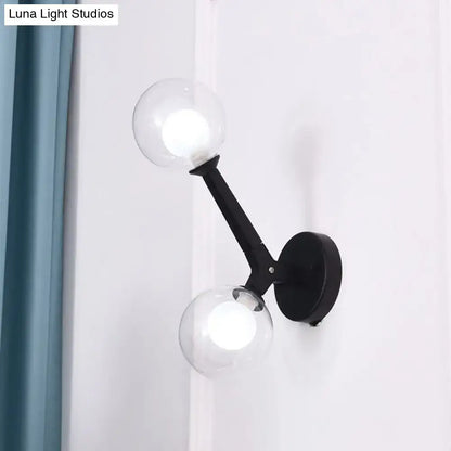 Black wall lamp with two clear glass globe shades featuring modern gold and black double globe wall design