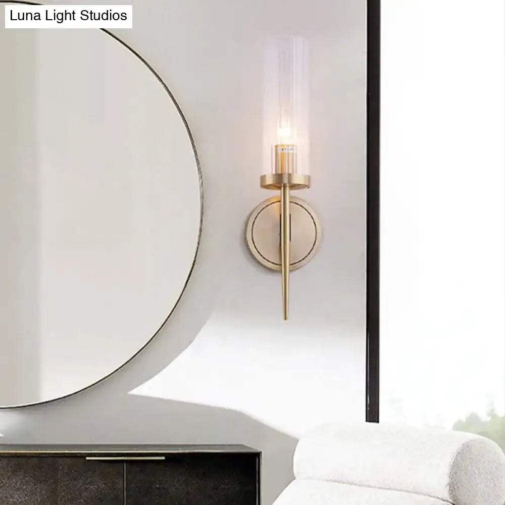 Modern brass-finished wall lamp with clear fluted glass cylinder for bedroom sconce lighting