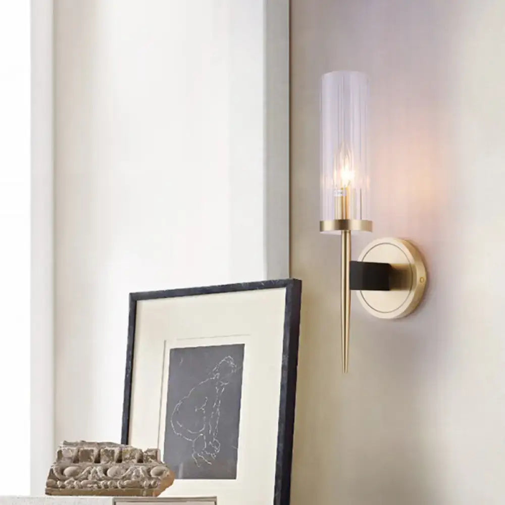 Gold-toned wall lamp with clear fluted glass shade and black accent bar for modern bedroom sconce lighting