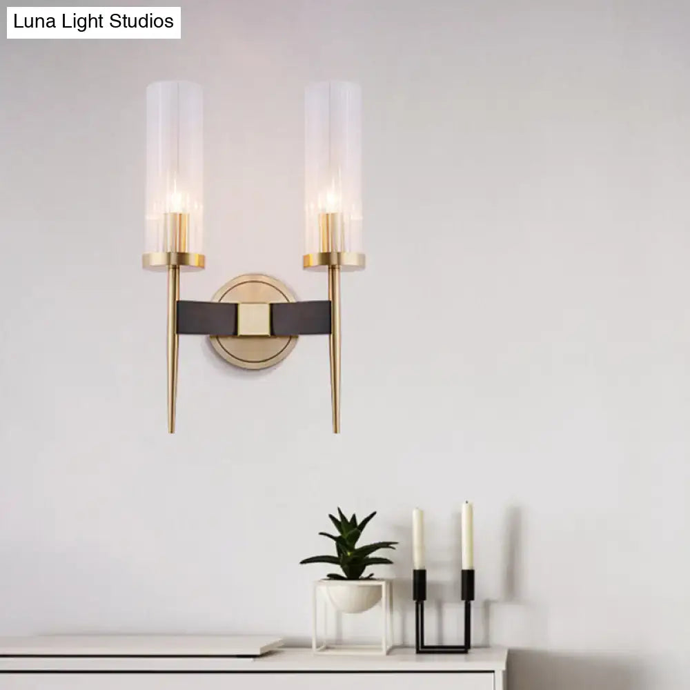 Modern two-light wall lamp with gold metal arms, fluted frosted glass shades, and black leather strap accent