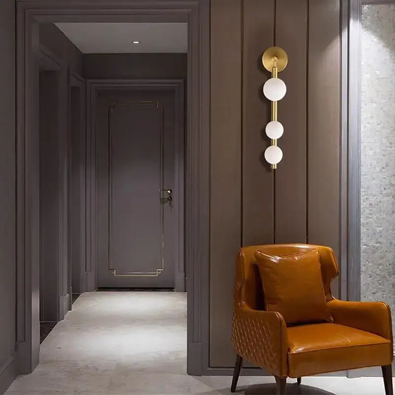 Warm amber leather armchair with quilted detailing and cushion paired with decorbites glass ball wall lights