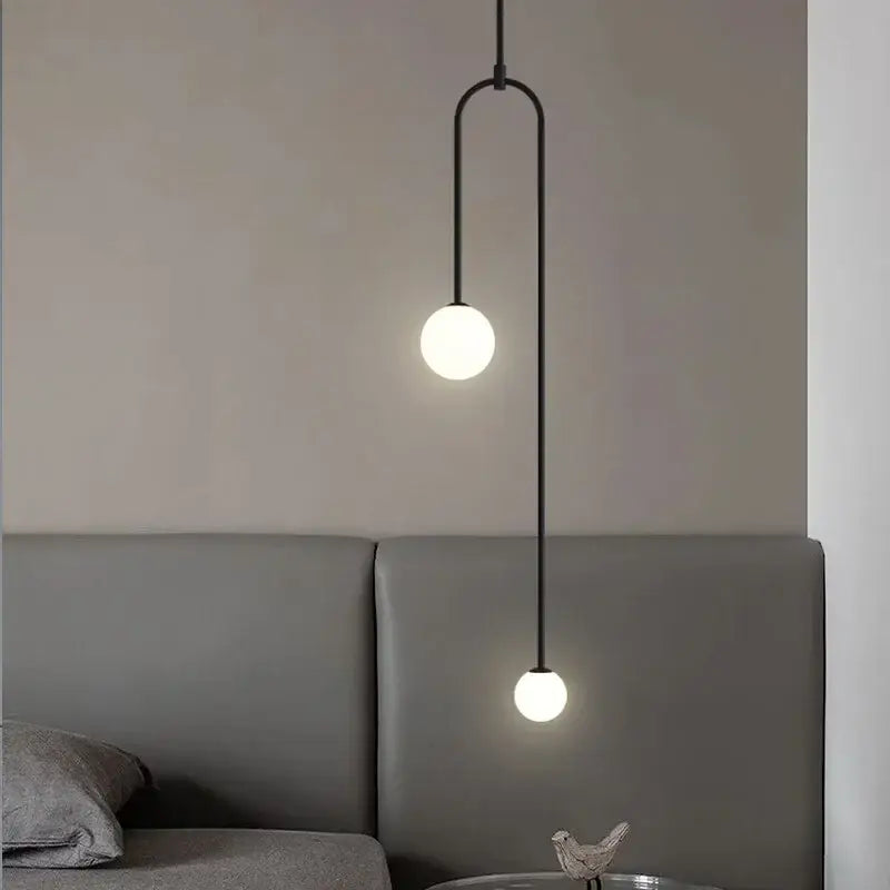 Black minimalist pendant light with two frosted glass globe bulbs and curved metal detailing for dining room use