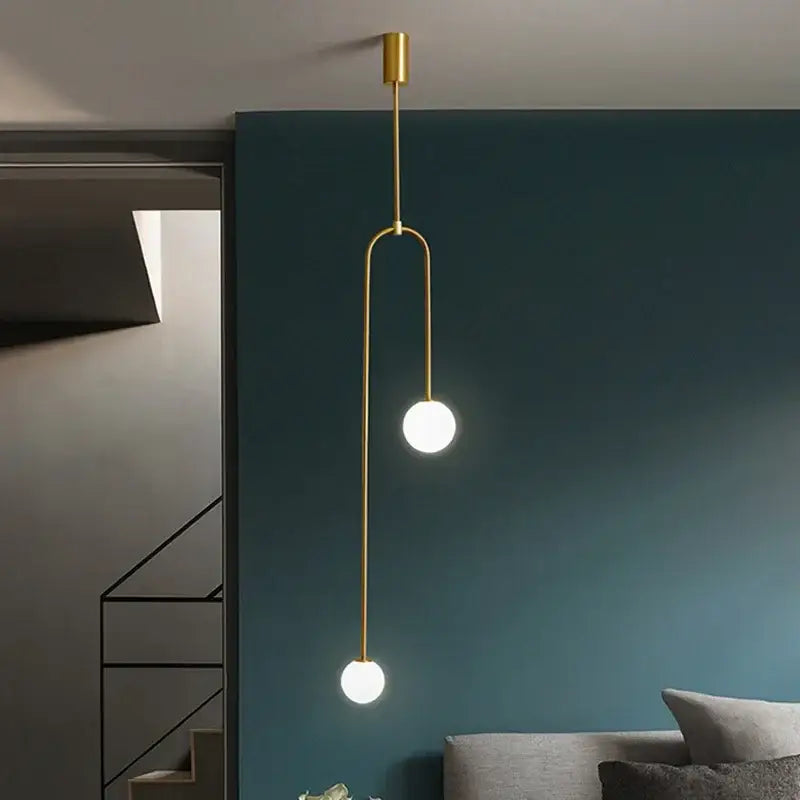 Modern gold pendant light with two white glass globe bulbs and sleek metal detailing for dining room use