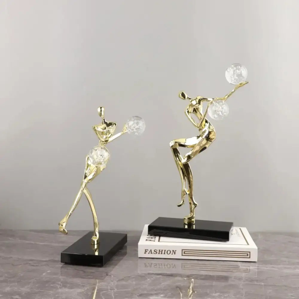 Modern gold and black decorbites golden man crystal ball sculpture with stylized dancers on black rectangular bases