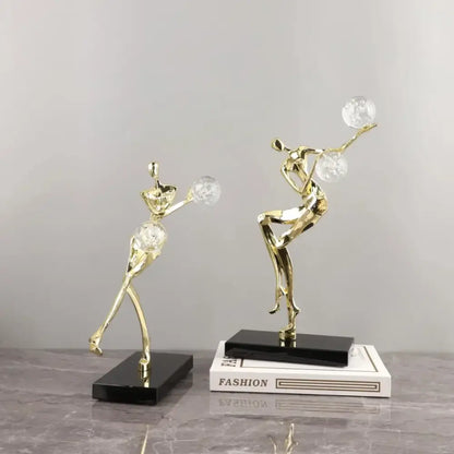Modern gold and black decorbites golden man crystal ball sculpture with stylized dancers on black rectangular bases