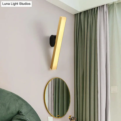 Modern gold and black wall sconce with rectangular LED fixture width and sleek black circular mounting base for living room