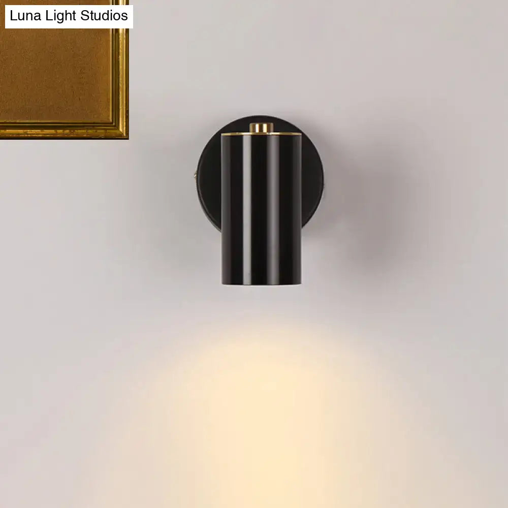 Modern gold and black metallic tube led light bedside wall sconce with black cylindrical body and gold accent emitting warm light