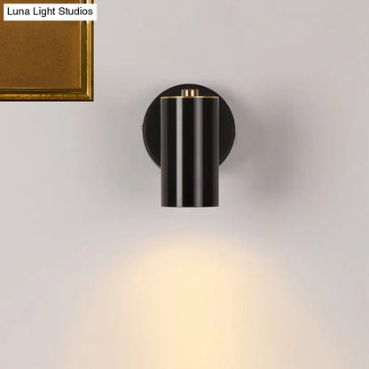 Modern gold and black metallic tube led light bedside wall sconce with black cylindrical body and gold accent emitting warm light