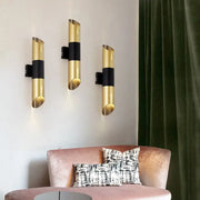 Three modern gold and black rotatable cylinder wall sconces with sleek curved design for bedroom lighting