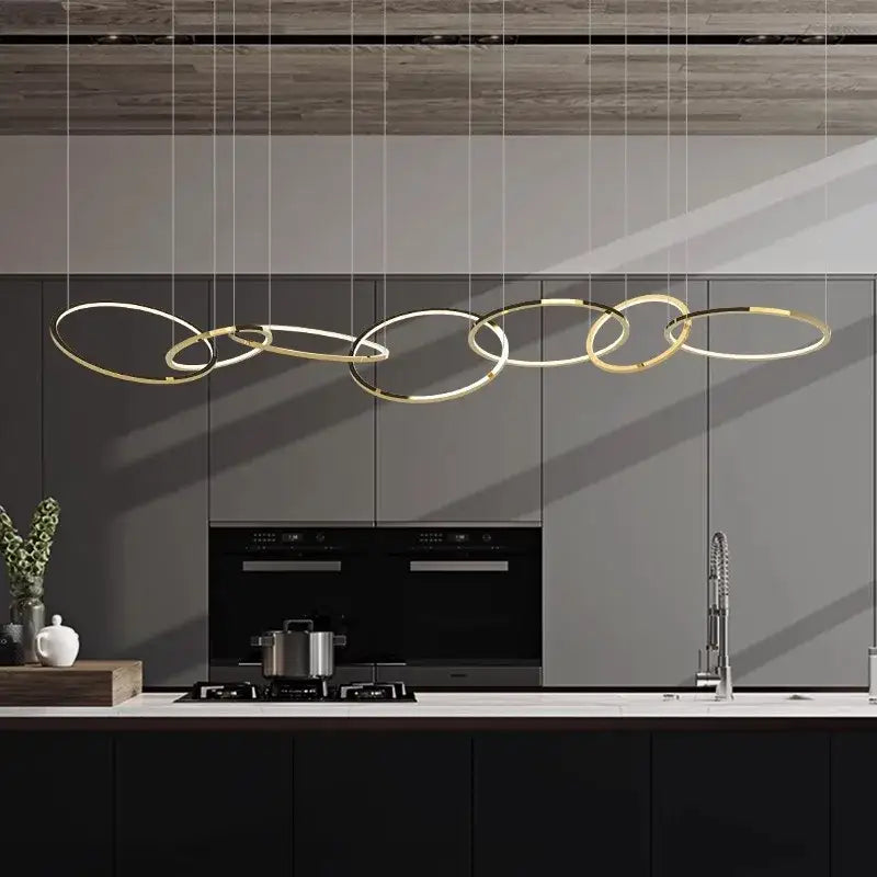 Modern gold stainless steel pendant lights with interconnected rings above a sleek kitchen counter decorbites gold stainless