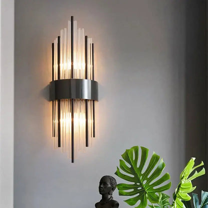 Modern gold and black stainless steel wall sconce with sleek metallic base and vertical glass rods emitting warm light
