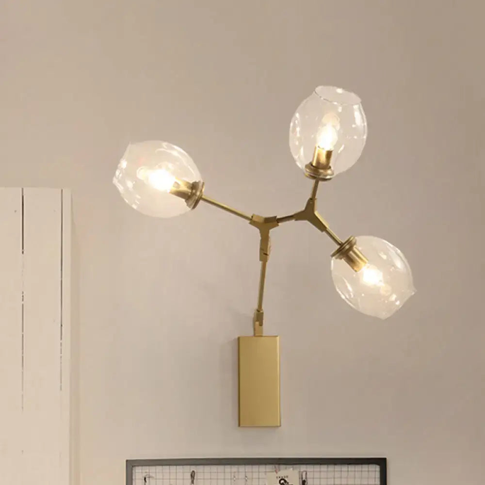 Modern gold wall lamp with three clear glass bulbous shades designed for living room use