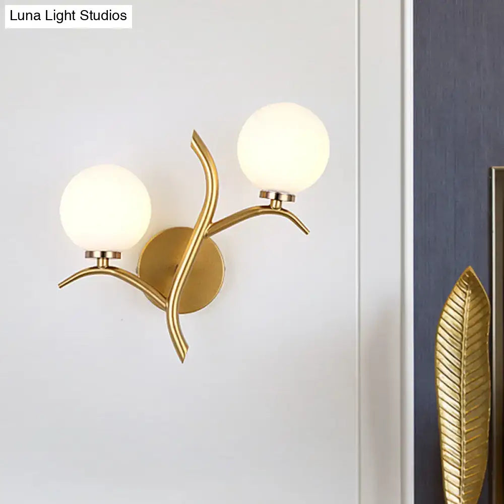 Modern gold branch wall light fixture with two frosted glass shades and leaf-like metal design for living room use