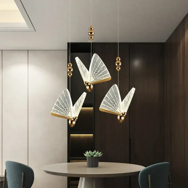 Three elegant decorbites butterfly led chandelier pendant lights with gold metal frames and white crystal mesh wings hang ceiling