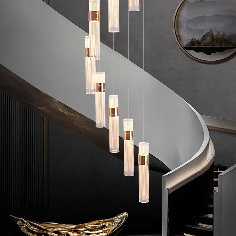 Modern gold cascading pendant light with frosted glass tubes and brushed brass accents featuring adjustable height for dining room