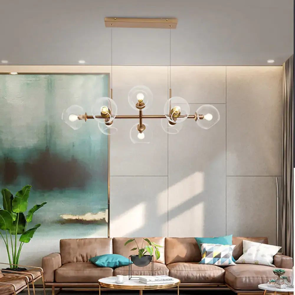 Modern gold chandelier with clear glass globe shades in brass metal designed for dining room lighting