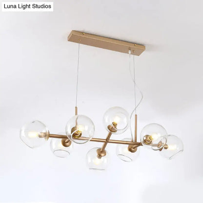 Modern gold chandelier with brass finish and clear glass globe shades for elegant dining room lighting