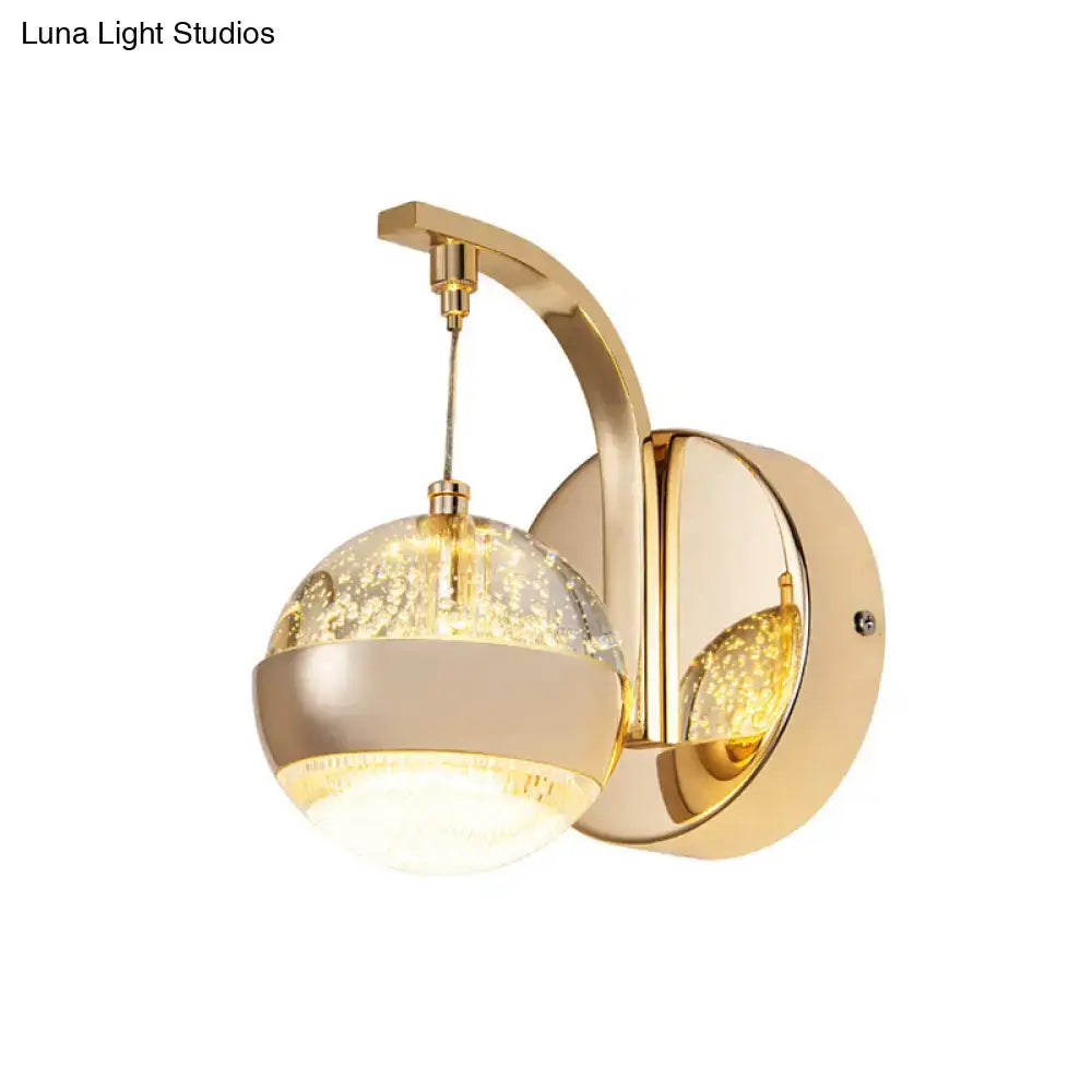Modern gold and chrome wall light featuring a spherical crystal ball with internal golden sparkles for bedroom lighting