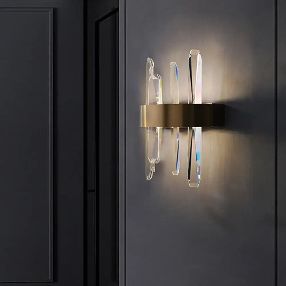 Modern gold clear crystal bar wall sconce with brushed brass base and clear crystal arms refracting warm light for bedroom