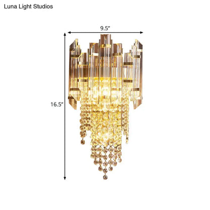 Modern gold wall lamp with clear crystal and amber glass prisms in a cascading tiered sconce design for bedroom use