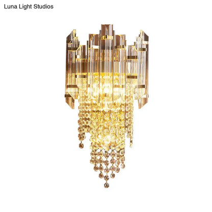 Modern gold wall lamp with clear crystal cascading beads and geometric glass panels for elegant bedroom lighting
