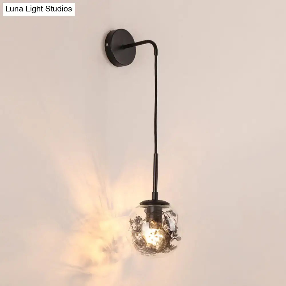 Black metal wall light with clear glass spherical globe featuring delicate flower deco cloth etchings for bedroom decor