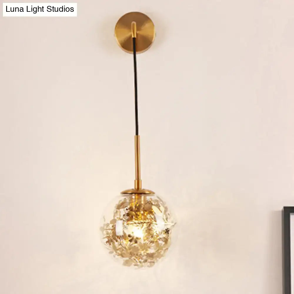 Modern gold-toned spherical wall light with clear glass faceted globe and black cord for flower deco cloth decor