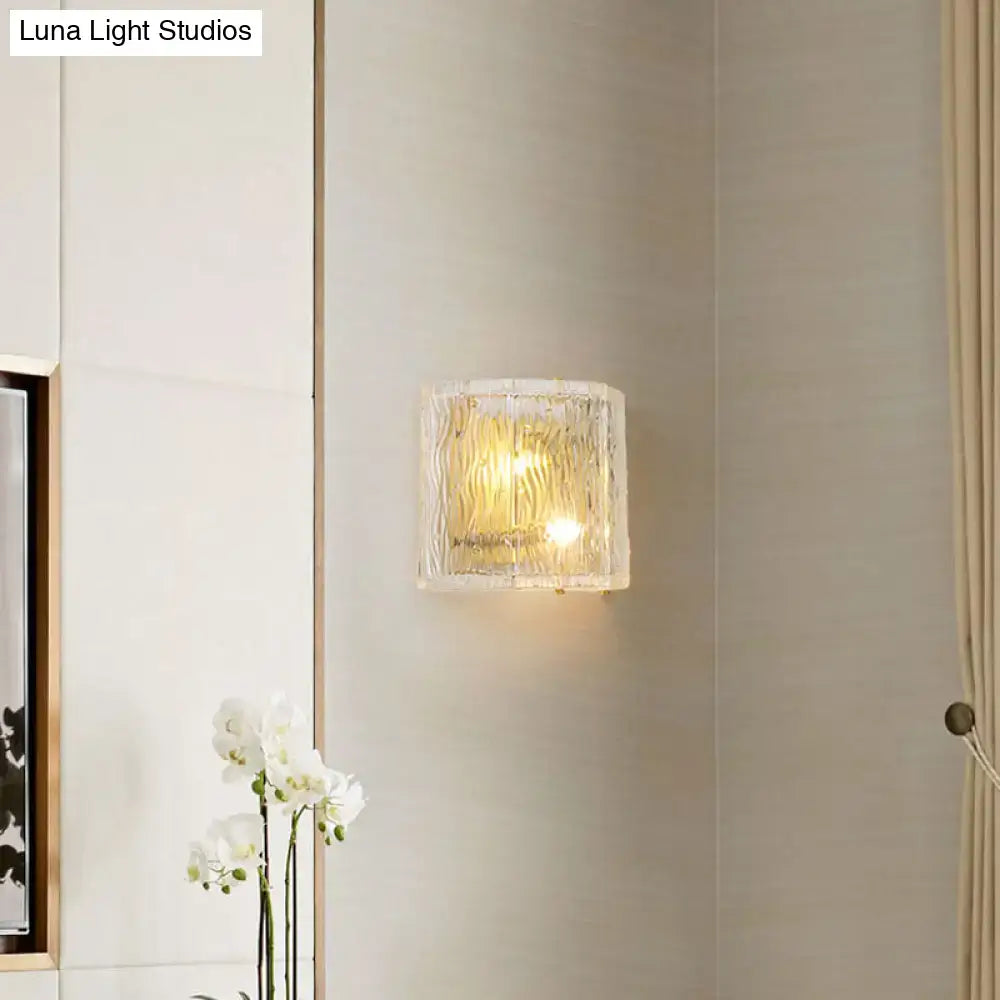 Modern gold clear ripple glass wall sconce with a square textured translucent shade diffusing warm wall light