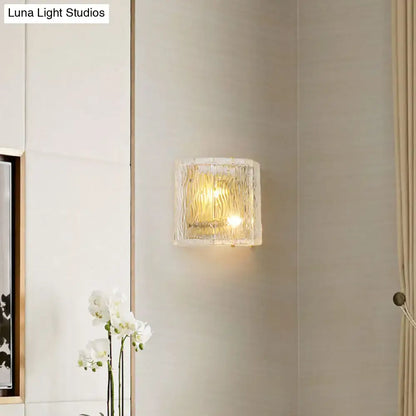 Modern gold clear ripple glass wall sconce with a square textured translucent shade diffusing warm wall light