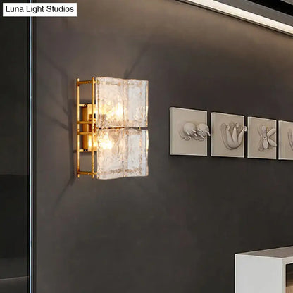 Modern gold two-light wall sconce with clear water glass textured shades for bedroom lighting