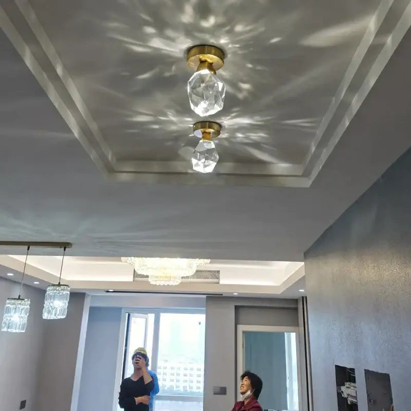 Two modern gold crystal aisle ceiling lights with gold-finished bases casting geometric shadows in hallway decorbites crystal aisle