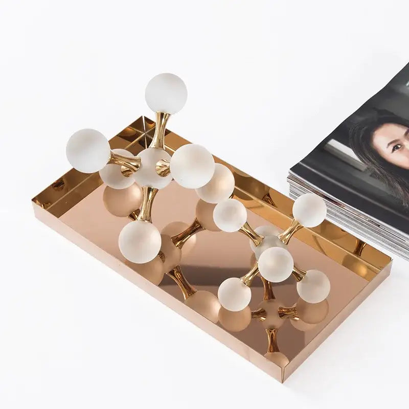Modern gold crystal ball molecule geometric ornament with frosted nodes and polished connectors on mirrored tray decorbites