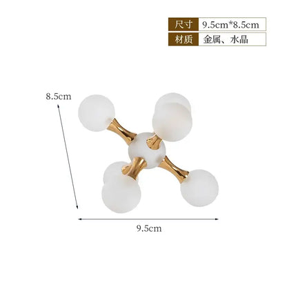 A modern gold crystal ball molecule geometric ornament with frosted white spheres on polished metal arms for decorbites decor